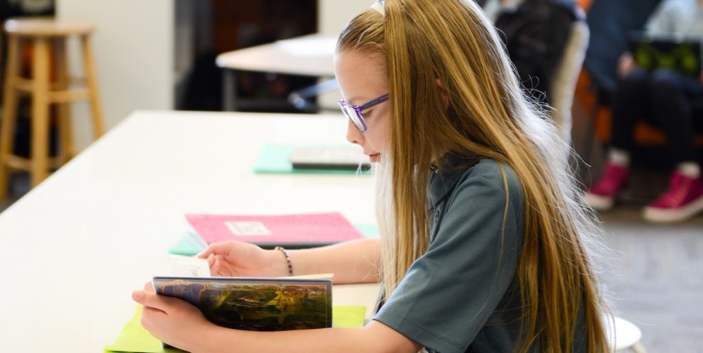 Young girl reading in class