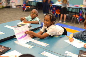 A little girl sharing her art with others in a classroom